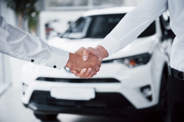 Close up of sales manager in black suit selling the car to the customer.
