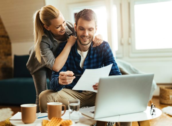 Happy couple analyzing their home budget while paying bill on a computer.